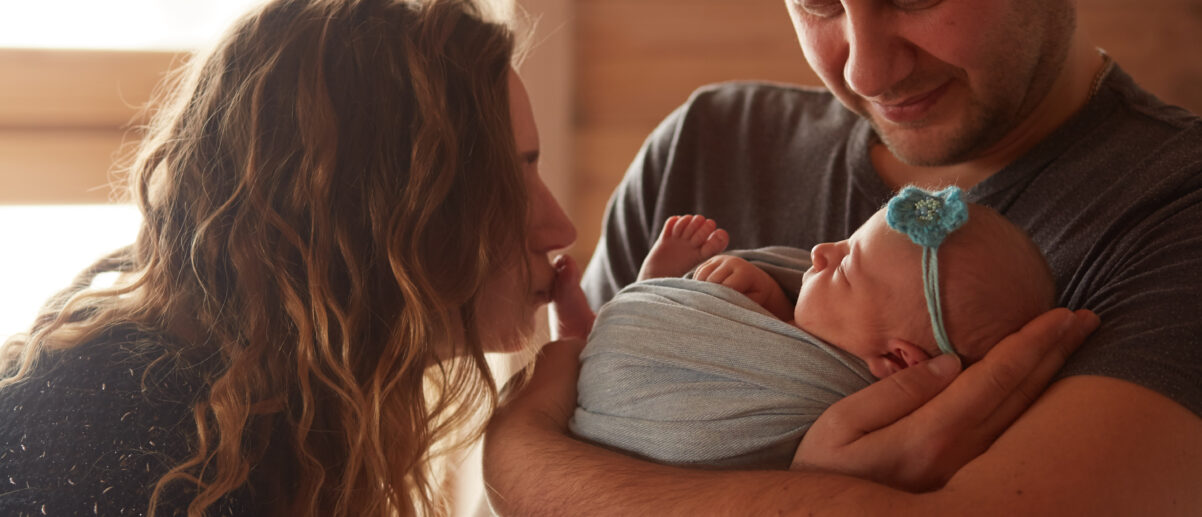 The mother and father embracing their daughter